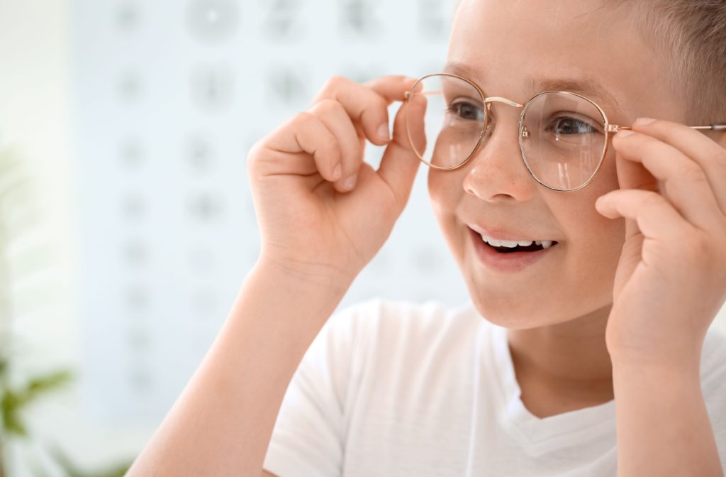 A young boy smiles as he tries on his glasses at an optometrist's clinic