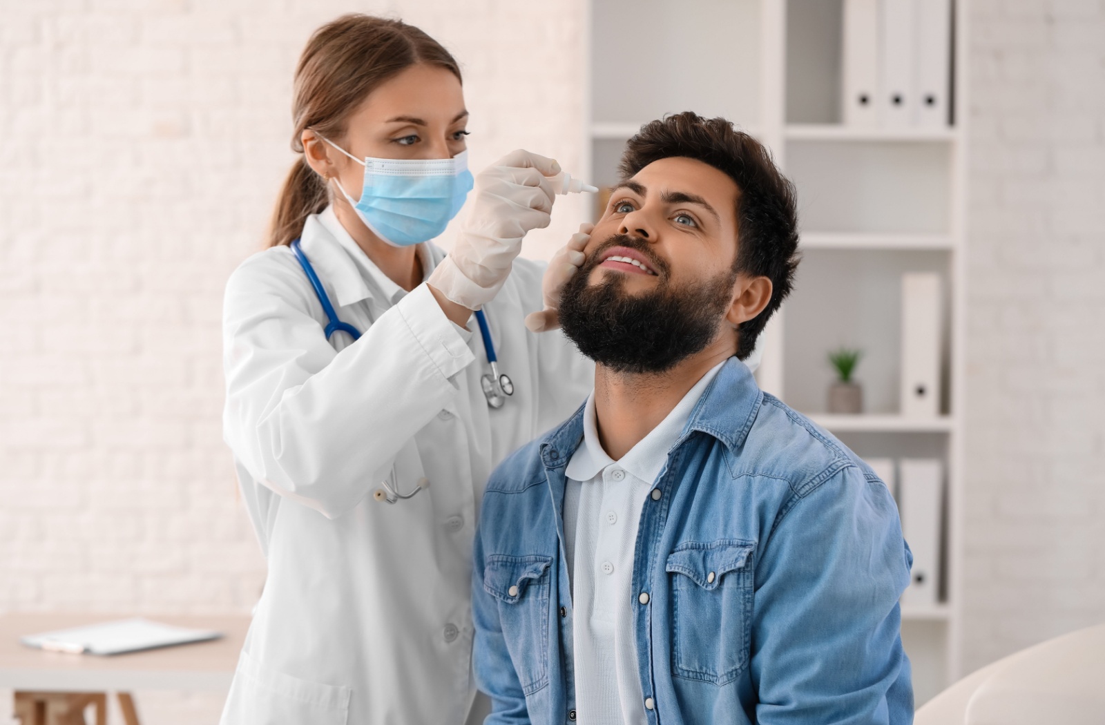 Doctor applying eye drops to a patient during an eye exam.