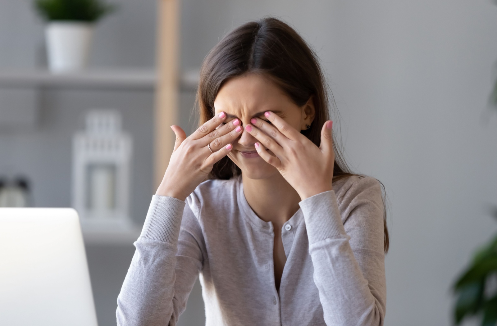 A young woman rubs her irritated eyes that were caused by wearing incompatible contact lenses for dry eyes.