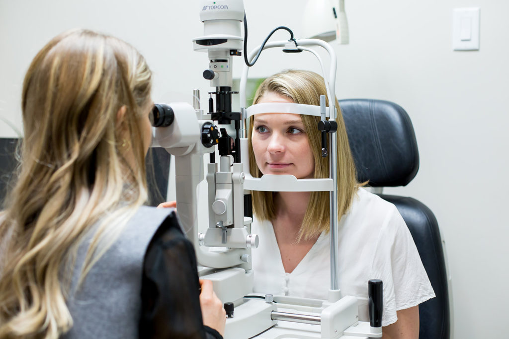 An eye doctor at Tutt Street Optometry measuring a young patient's eye during an eye exam.