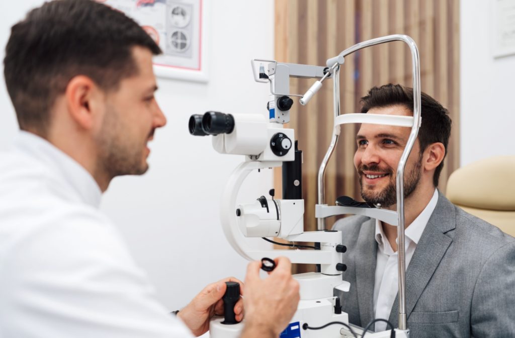 An optometrist prepares to examine a patient's eyes using a slit lamp during an eye exam.