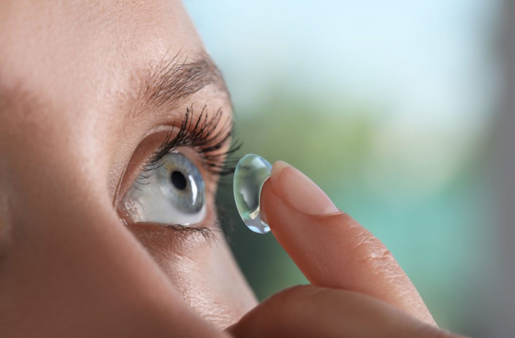 A close-up image of a person putting a contact lens into their left eye.