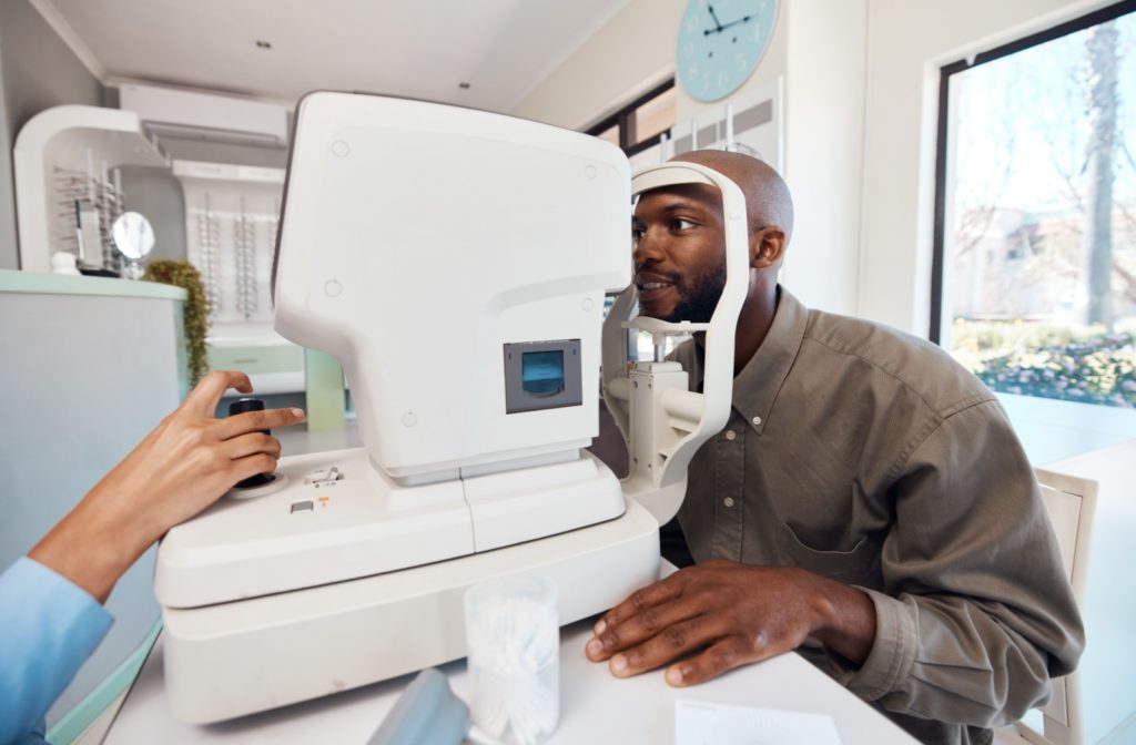 A patient smiling while an optometrist uses corneal tomography during a contact lens exam.