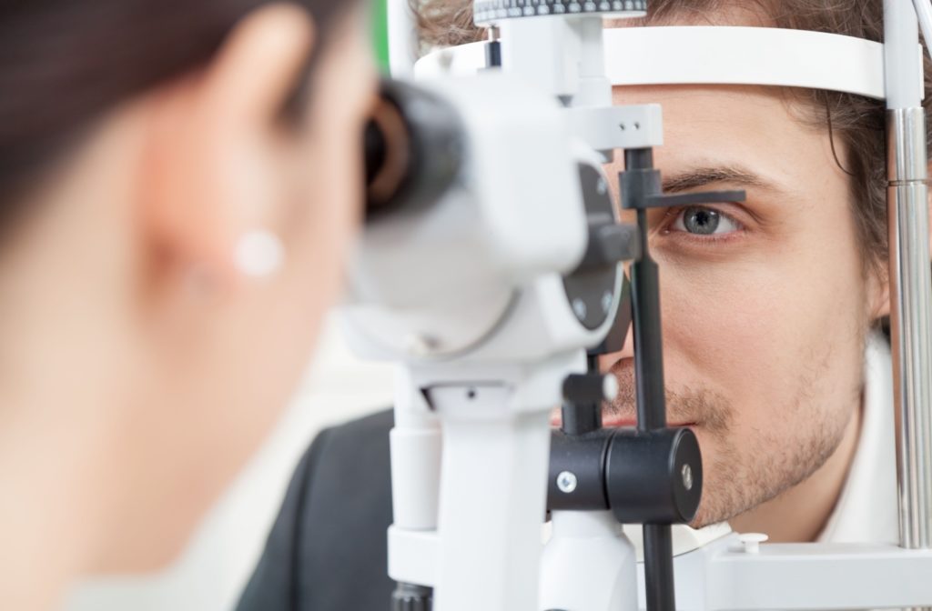 A close-up image of an optometrist examining a patient's eyes during a contact lens fitting.