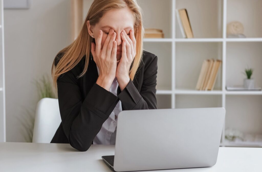 A person working on a laptop takes a break and rubs their sore eyes.