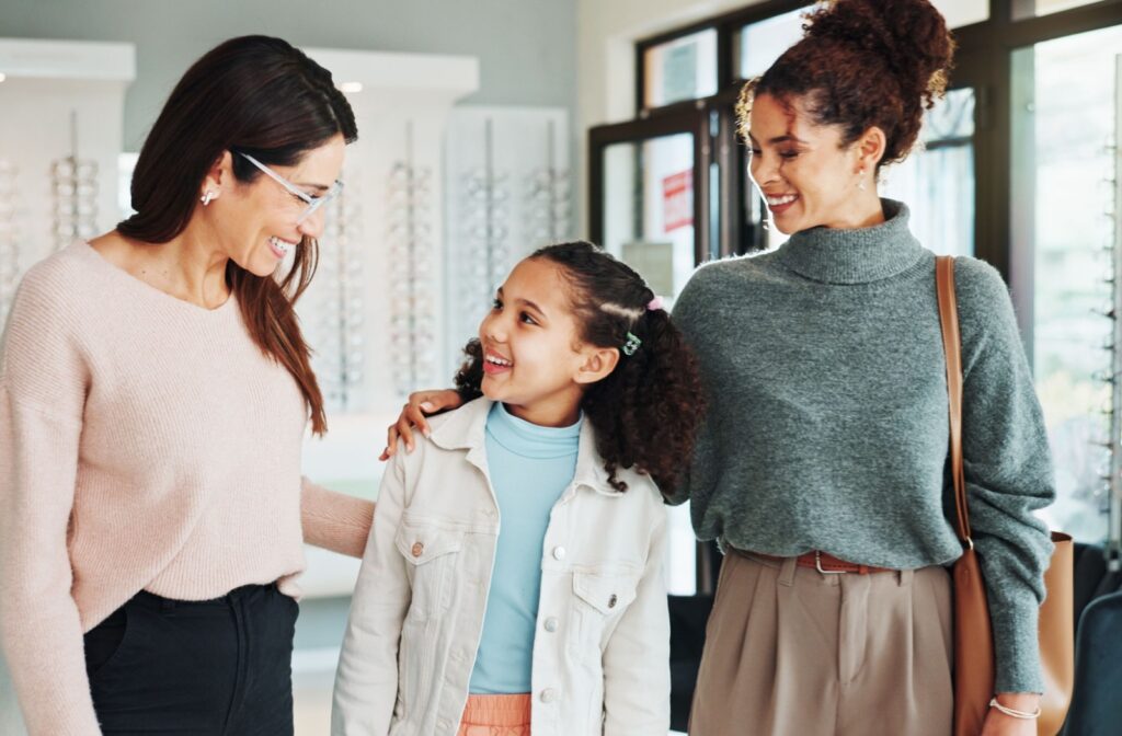 Child and parent smile while speaking with an optician in a bright, modern eyewear clinic