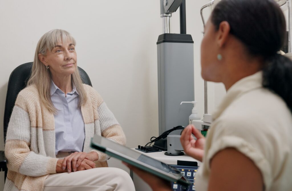 An eye doctor talks to a senior patient during an eye exam