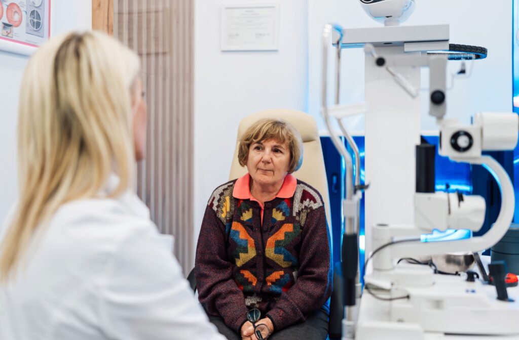 A senior sits in a chair at the eye doctors and talk to an optometrist